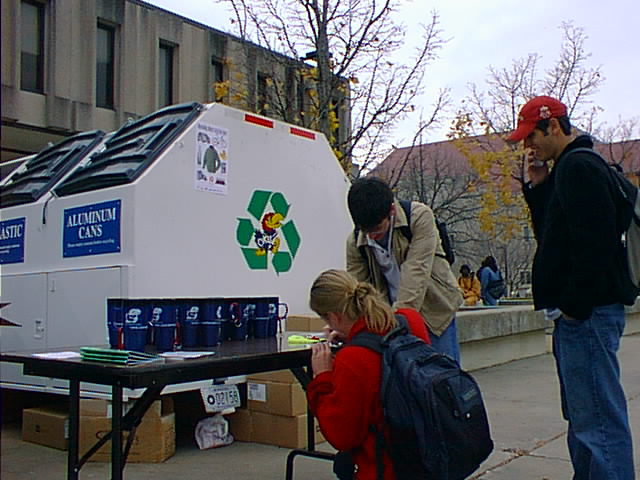 Students outside Wescoe in front of a large recycling container.