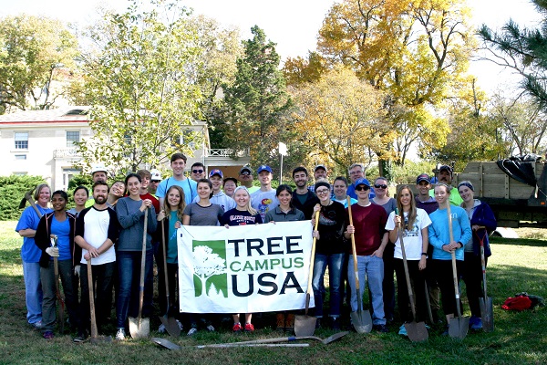 Group of about 30 people with shovels standing behind a banner that says "Tree Campus USA"