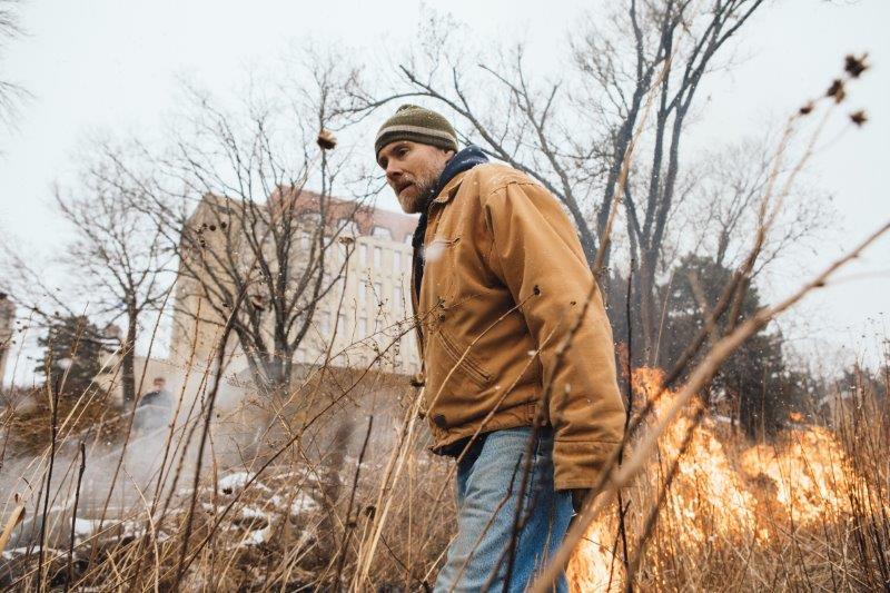 Person walking in front of a controlled burn of the Prairie Acre site.